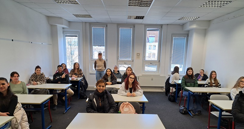 Die neuen Auszubildenden zu Erzieherinnen und Erziehern sitzen im Klassenraum an Tischen und posieren für ein Gruppenfoto.