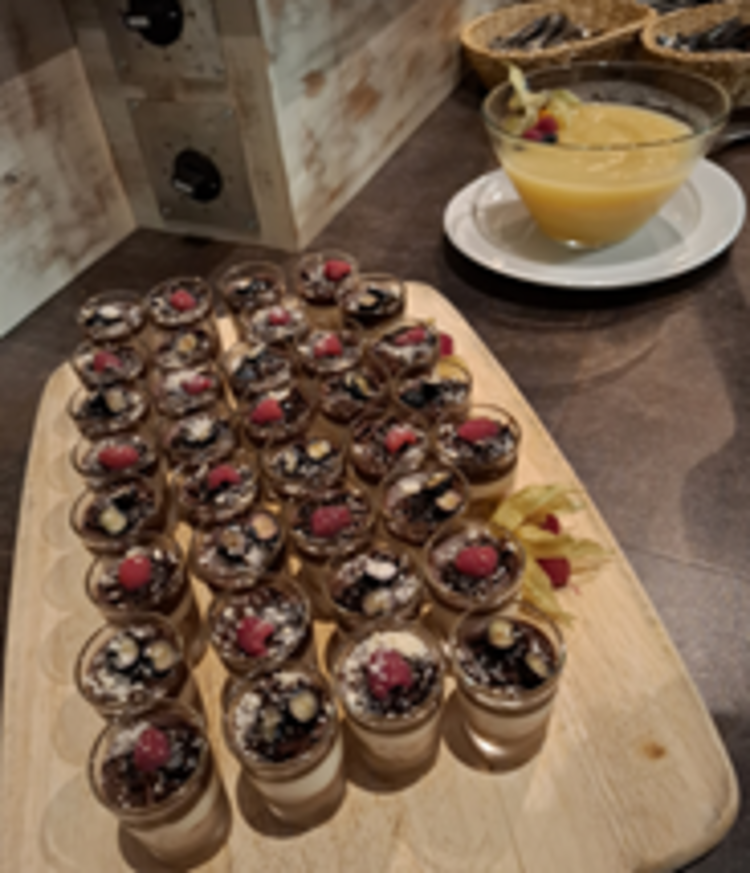 Räucherkerzen und ein Hauch von Weihnacht Holzbrett mit vielen kleinen Dessertgläsern, gefüllt mit geschichteter Creme und Schokostreuseln, jeweils mit Beeren und Nüssen garniert; dahinter eine Schale mit gelber Sauce.