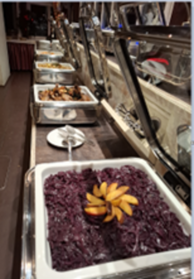 Räucherkerzen und ein Hauch von Weihnacht Buffettheke mit mehreren Edelstahlschalen, vorne Rotkohl mit dekorativ aufgefächerten Apfelscheiben, dahinter weitere warme Speisen.