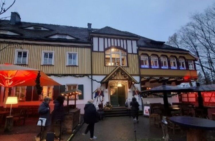 Räucherkerzen und ein Hauch von Weihnacht Abendliche Außenansicht des „Historischen Fischhauses“ mit beleuchtetem Eingang, Fachwerkfassade und Gästen, die über den Hof mit roten Schirmen zum Gebäude gehen.